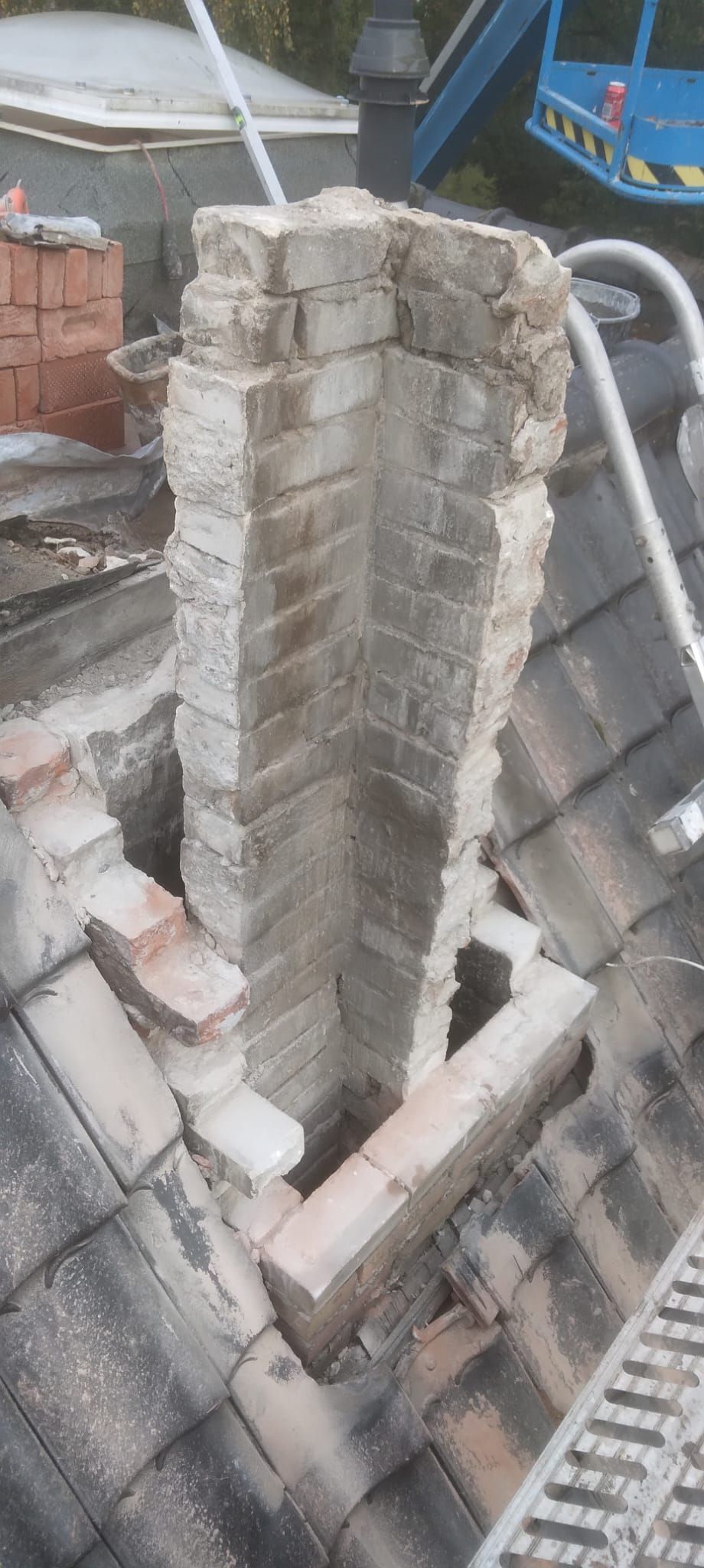 Schoorsteen met het metselwerk deels opengebroken, op een pannendak.